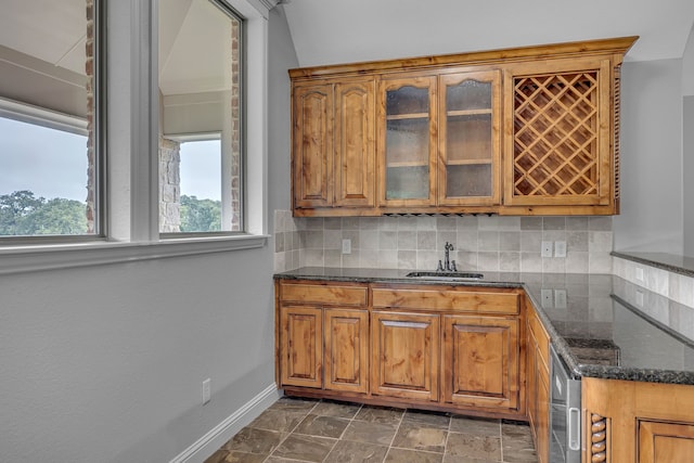 kitchen featuring dark stone counters, tasteful backsplash, and sink