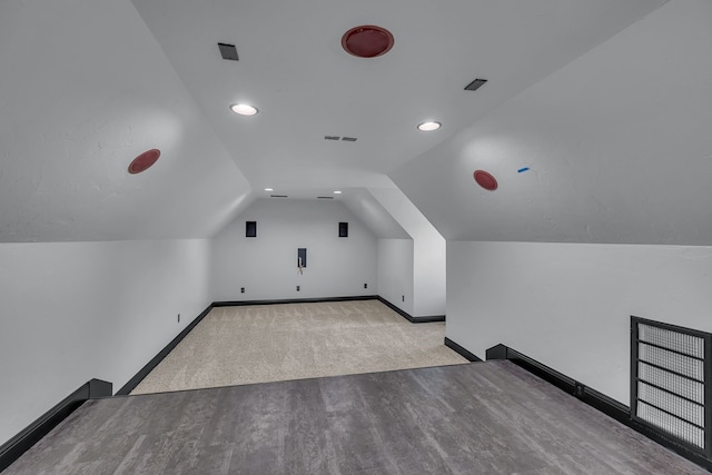 bonus room with light colored carpet and vaulted ceiling