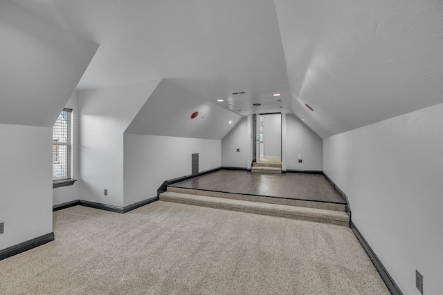 additional living space featuring carpet and vaulted ceiling