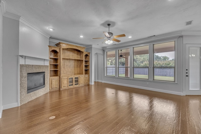 unfurnished living room featuring ceiling fan, a wealth of natural light, wood-type flooring, and ornamental molding