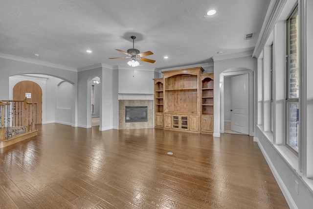 unfurnished living room with dark hardwood / wood-style flooring, ceiling fan, and crown molding