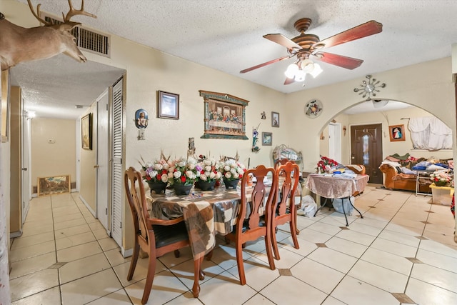 tiled dining space with a textured ceiling and ceiling fan