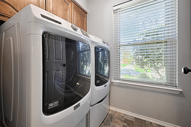 clothes washing area with cabinets and washer and dryer