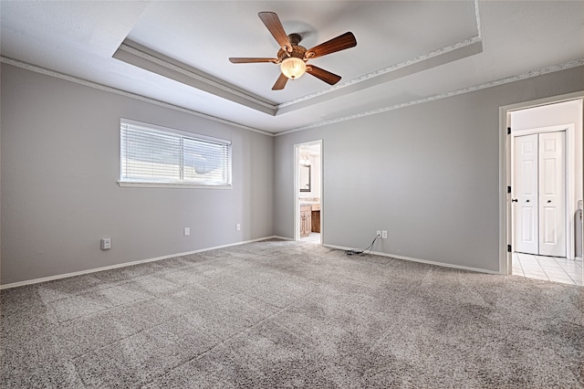 spare room with ceiling fan, light colored carpet, ornamental molding, and a tray ceiling