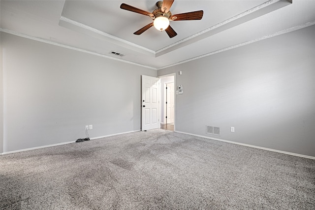 carpeted spare room featuring a tray ceiling, crown molding, and ceiling fan