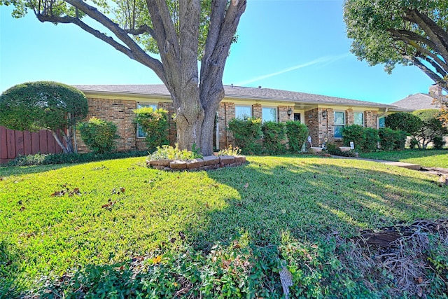 ranch-style home featuring a front yard, fence, and brick siding