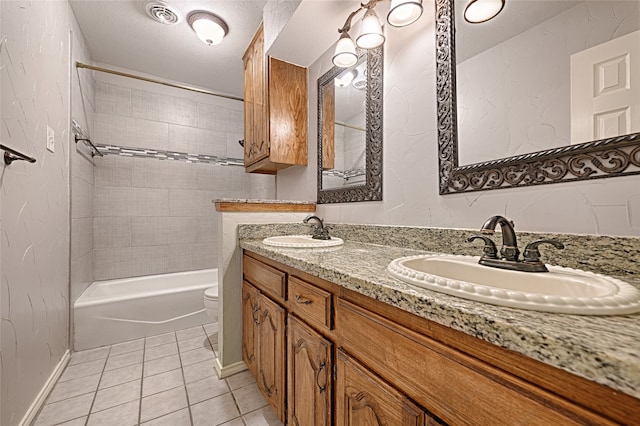 full bathroom with tiled shower / bath combo, tile patterned floors, a textured ceiling, toilet, and vanity