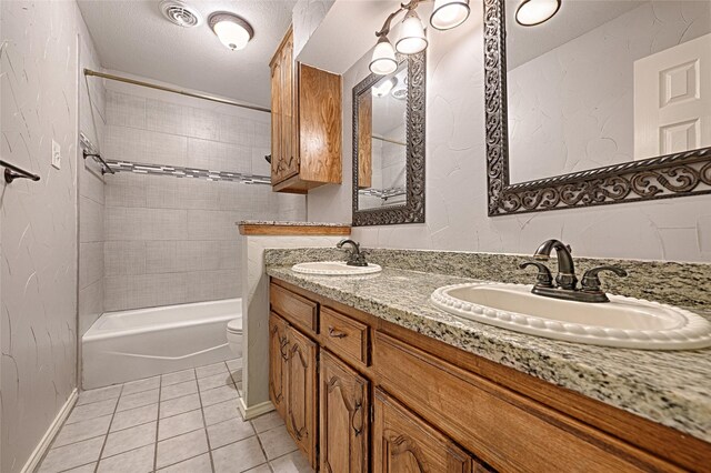 full bathroom with tiled shower / bath combo, tile patterned floors, a textured ceiling, toilet, and vanity