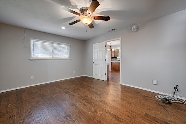 empty room featuring ceiling fan with notable chandelier and dark wood-type flooring