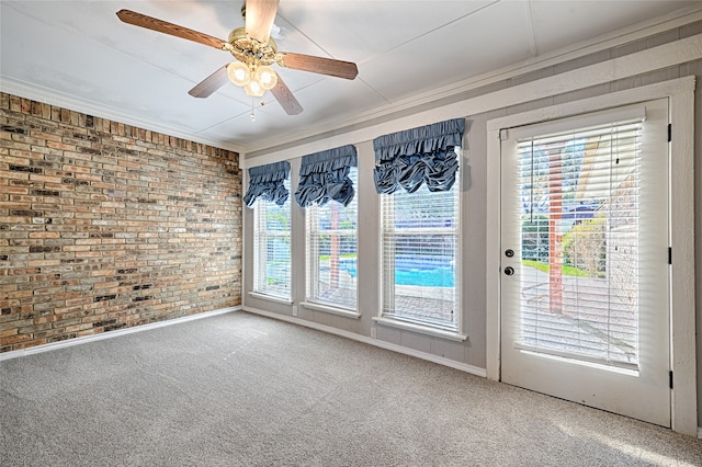 empty room featuring ceiling fan, crown molding, carpet, and brick wall