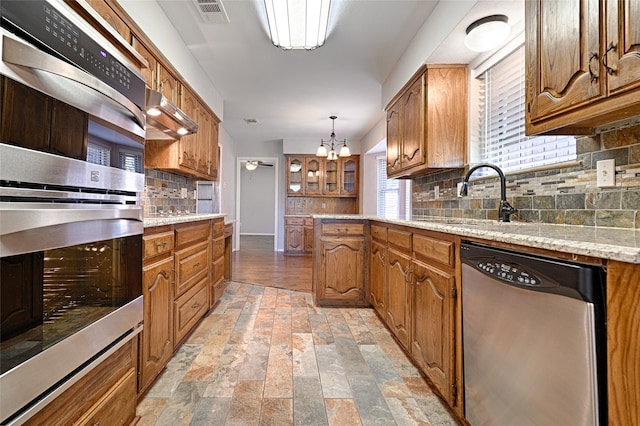 kitchen featuring a chandelier, appliances with stainless steel finishes, tasteful backsplash, and pendant lighting