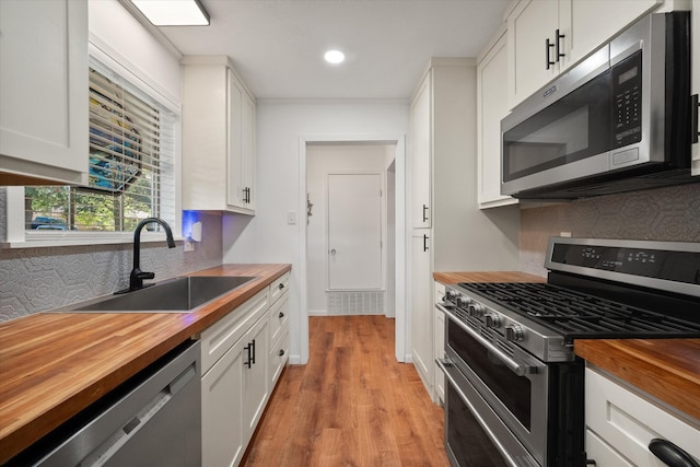 kitchen featuring appliances with stainless steel finishes, sink, light hardwood / wood-style flooring, butcher block countertops, and white cabinetry