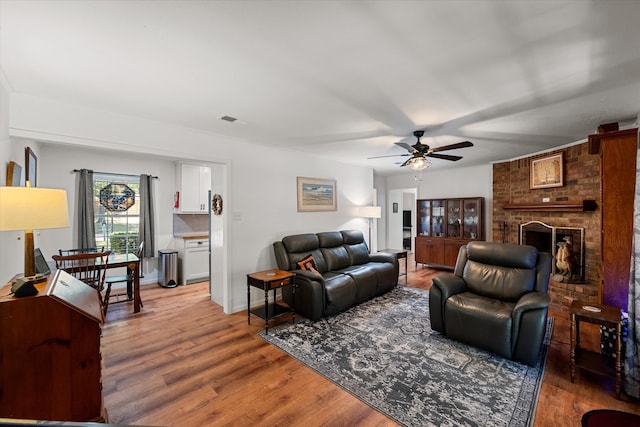 living room featuring hardwood / wood-style flooring, ceiling fan, and a fireplace