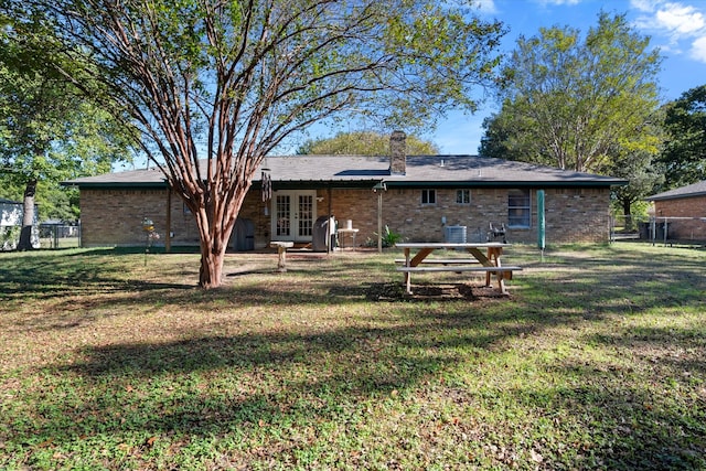 rear view of house featuring french doors and a lawn