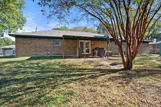 rear view of house with a lawn and french doors