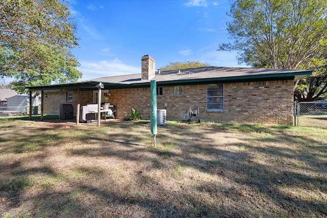 back of house featuring a yard and central AC