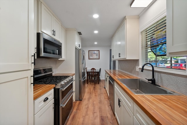 kitchen featuring white cabinetry, sink, wooden counters, appliances with stainless steel finishes, and light wood-type flooring