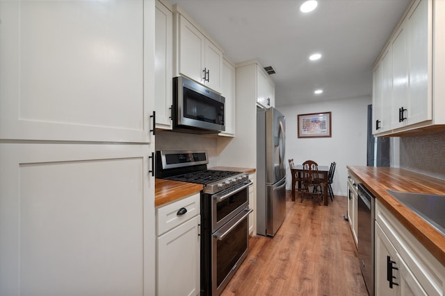 kitchen featuring white cabinets, wood counters, light hardwood / wood-style floors, and stainless steel appliances