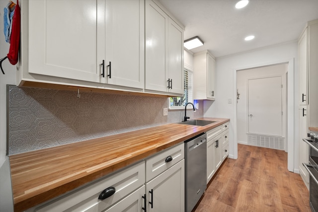 kitchen with wood counters, white cabinets, dishwasher, and sink