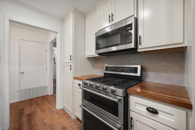 kitchen with butcher block countertops, white cabinetry, stainless steel appliances, and light hardwood / wood-style floors