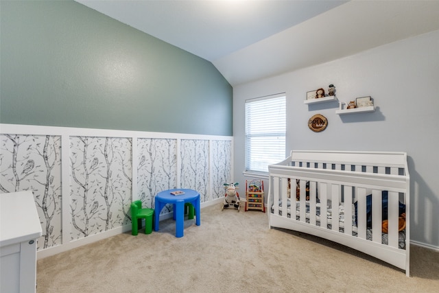 bedroom featuring a crib, carpet floors, and lofted ceiling