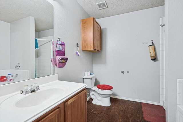 bathroom with vanity, a textured ceiling, a shower, hardwood / wood-style flooring, and toilet