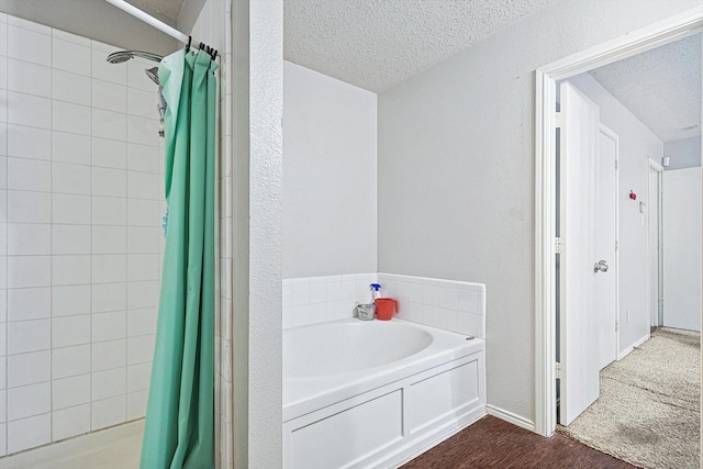 bathroom with hardwood / wood-style floors, separate shower and tub, and a textured ceiling