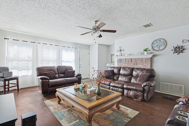 living room featuring a textured ceiling, ceiling fan, dark hardwood / wood-style floors, and a brick fireplace