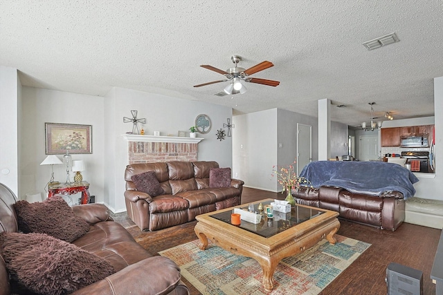 living room with dark hardwood / wood-style floors, a fireplace, a textured ceiling, and ceiling fan