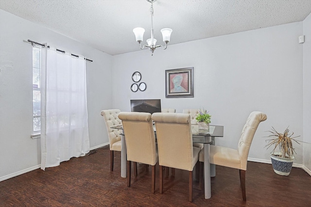 dining space featuring dark wood-type flooring, a textured ceiling, and a notable chandelier