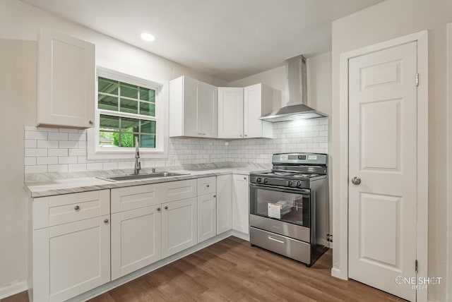 kitchen with dark wood-type flooring, wall chimney range hood, sink, stainless steel range oven, and white cabinetry