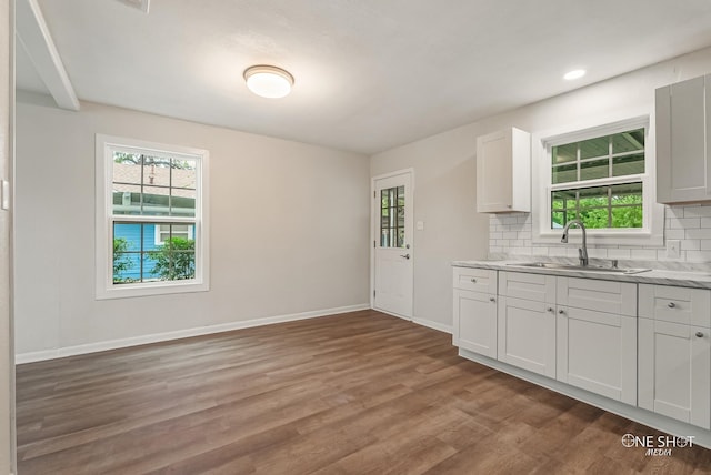 kitchen with tasteful backsplash, white cabinetry, sink, and hardwood / wood-style floors