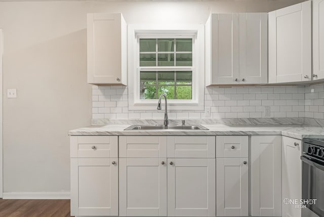 kitchen featuring backsplash, dark wood-type flooring, sink, white cabinets, and range