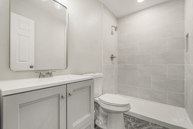 bathroom featuring vanity, toilet, and a tile shower