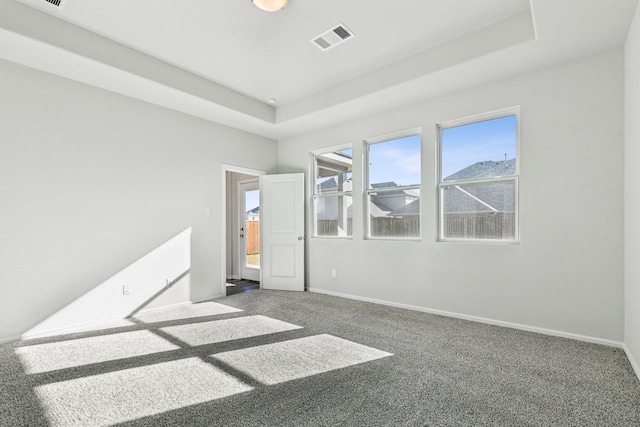 carpeted empty room with a tray ceiling