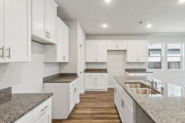 kitchen with white cabinets, stone counters, and sink