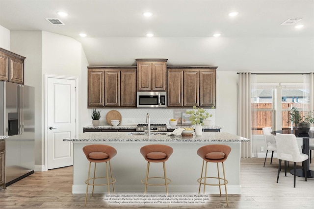 kitchen featuring a breakfast bar, stainless steel appliances, and an island with sink