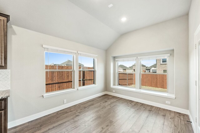 unfurnished dining area featuring hardwood / wood-style flooring and vaulted ceiling