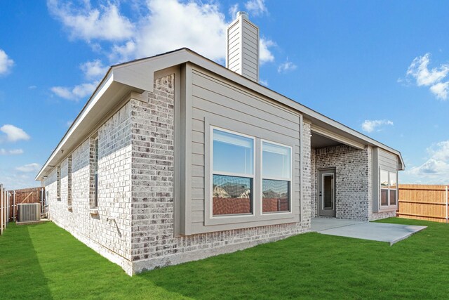 rear view of house featuring a yard, a patio, and central air condition unit