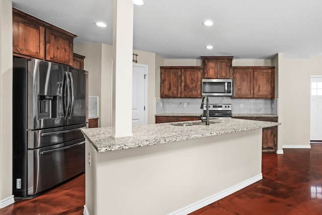 kitchen with tasteful backsplash, light stone counters, a center island with sink, and stainless steel appliances