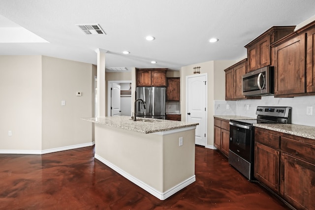 kitchen with stainless steel appliances, light stone countertops, an island with sink, and tasteful backsplash