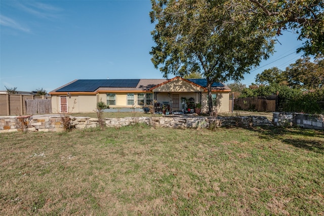 rear view of property with solar panels and a yard