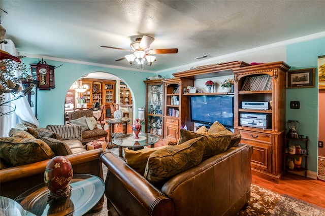 living room featuring dark hardwood / wood-style flooring, a textured ceiling, ceiling fan, and crown molding