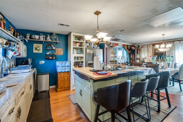 kitchen featuring a center island, a notable chandelier, stainless steel fridge, and light hardwood / wood-style flooring