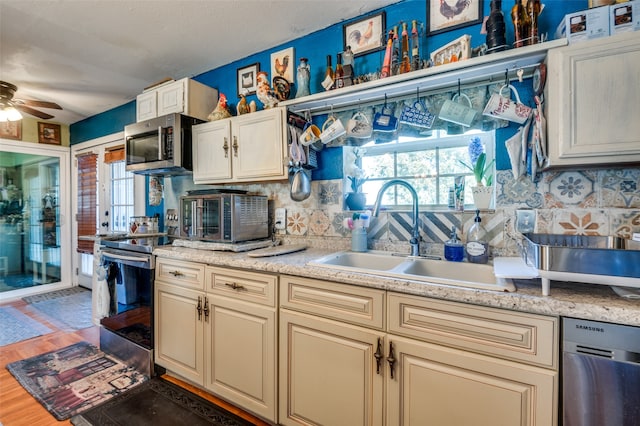 kitchen with cream cabinets, appliances with stainless steel finishes, dark hardwood / wood-style flooring, sink, and ceiling fan