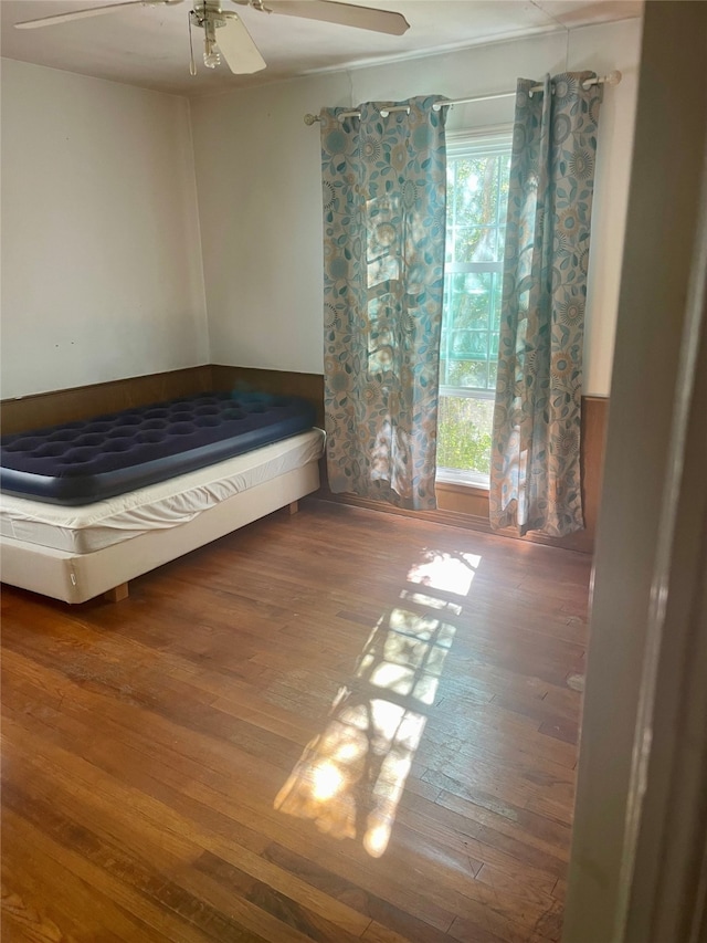 unfurnished bedroom featuring hardwood / wood-style flooring, multiple windows, and ceiling fan