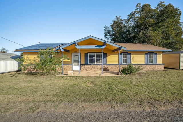 ranch-style house with solar panels and a front lawn