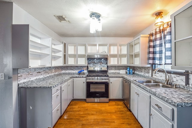 kitchen with stainless steel appliances, sink, tasteful backsplash, gray cabinets, and light wood-type flooring