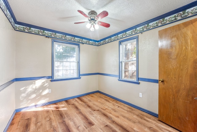 empty room featuring wood-type flooring, a healthy amount of sunlight, and crown molding