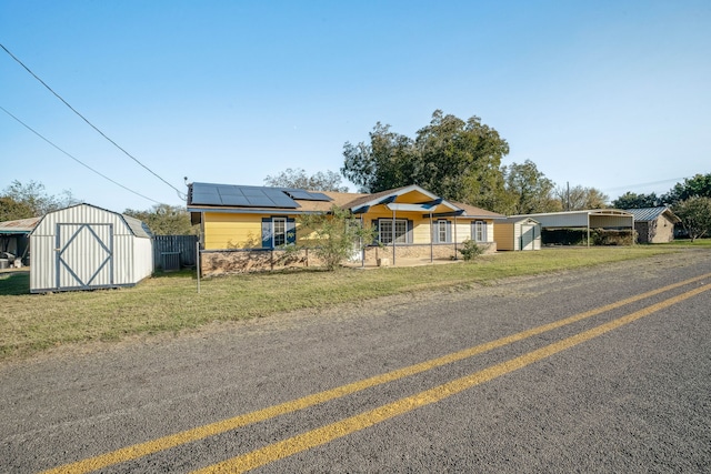 single story home with a front lawn, a storage unit, and solar panels